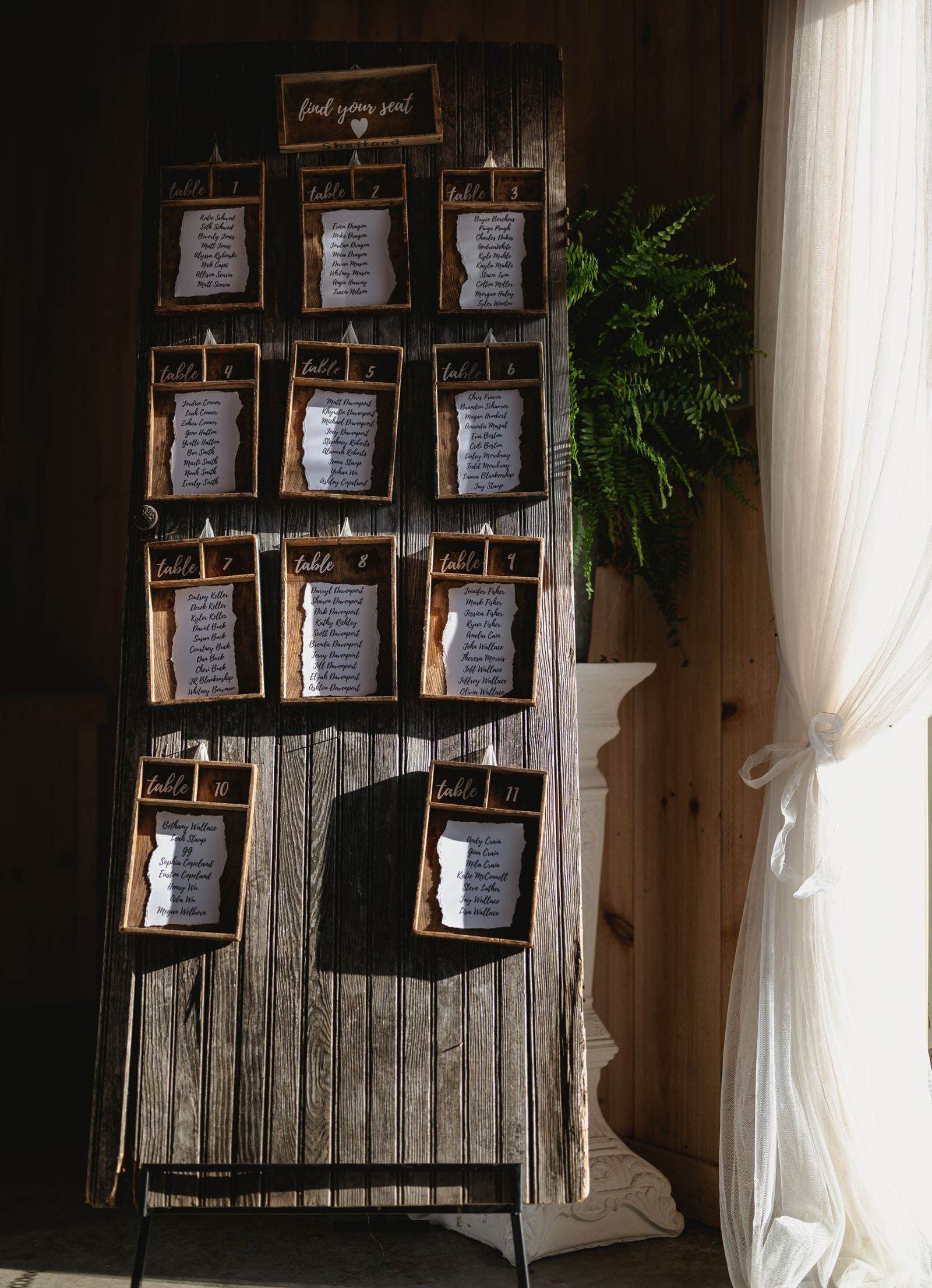 A wooden find-your-seat board listing guests by table